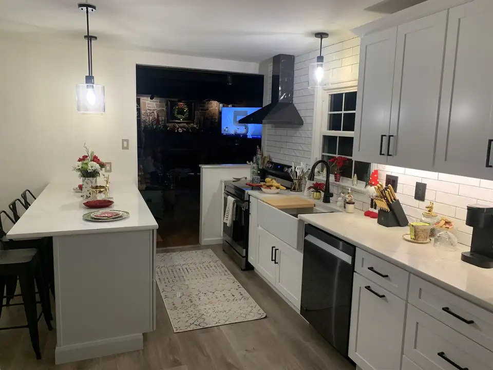 Kitchen and bath remodeling by Kelly's Kitchen and Bath: white shaker kitchen with subway tile backsplash, black range hood, island and pendant lights